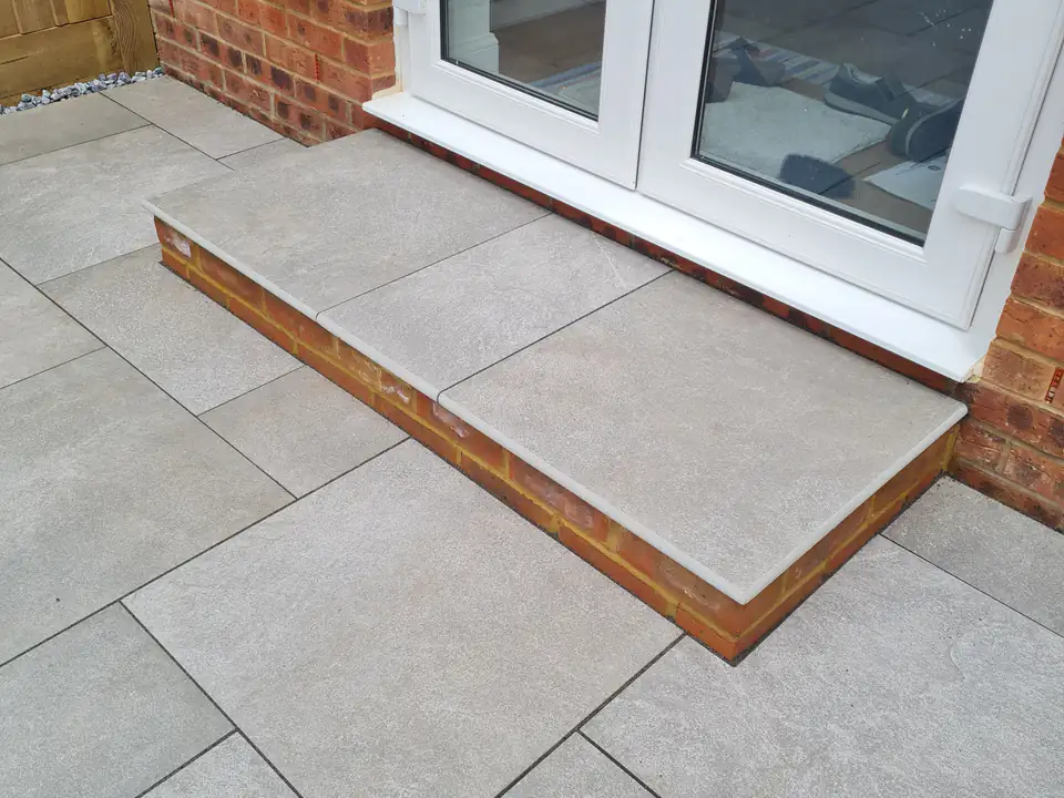 Light porcelain patio with a step up to French doors